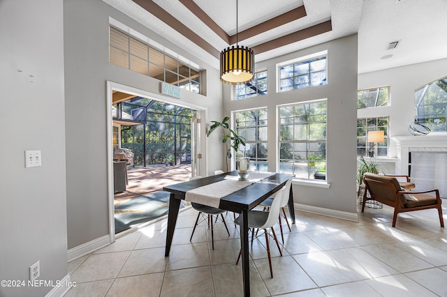 dining area with a healthy amount of sunlight, light tile patterned floors, and a towering ceiling