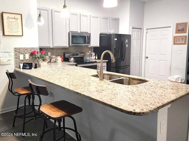 kitchen featuring a breakfast bar area, appliances with stainless steel finishes, white cabinetry, backsplash, and kitchen peninsula