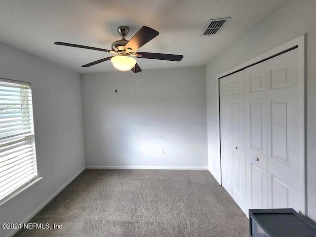 unfurnished bedroom featuring carpet floors, ceiling fan, and a closet