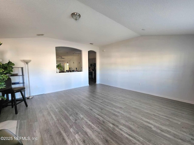 spare room with lofted ceiling, hardwood / wood-style floors, and a textured ceiling