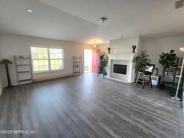 unfurnished living room with dark wood-type flooring, a textured ceiling, and a fireplace