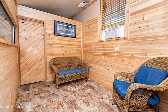 living area featuring wooden walls, a textured ceiling, and cooling unit