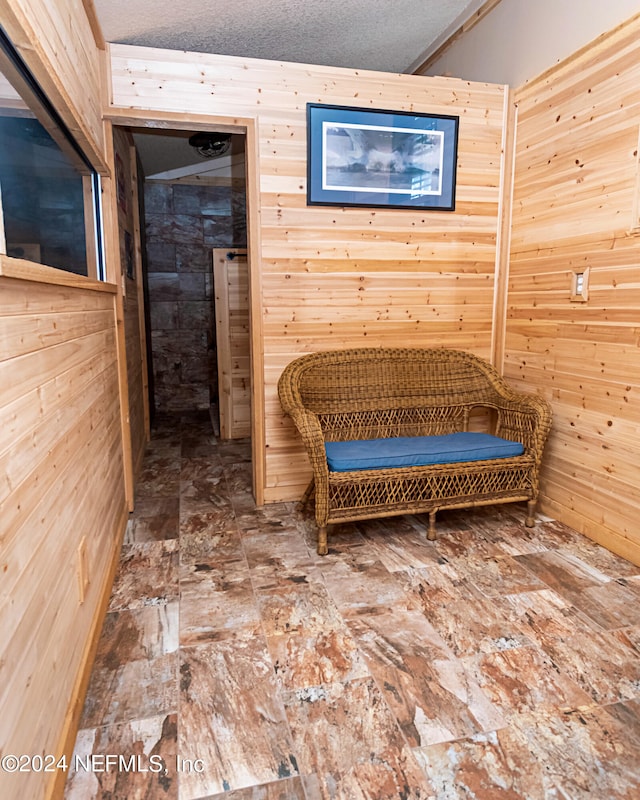 living area with wood walls and a textured ceiling