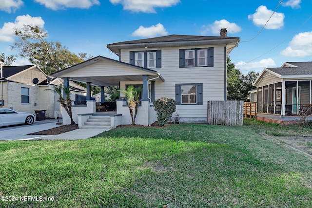 view of front of house with a front yard and a sunroom