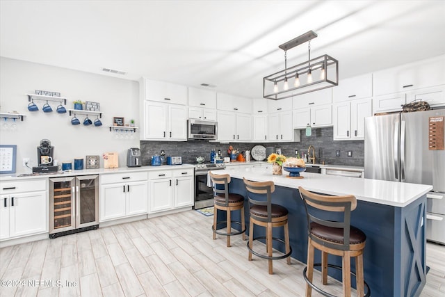 kitchen featuring beverage cooler, stainless steel appliances, hanging light fixtures, white cabinets, and a center island