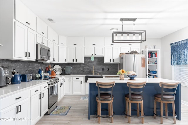 kitchen featuring decorative backsplash, a center island, stainless steel appliances, white cabinets, and a kitchen breakfast bar