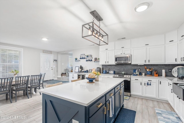 kitchen featuring light hardwood / wood-style floors, blue cabinets, pendant lighting, stainless steel appliances, and white cabinets