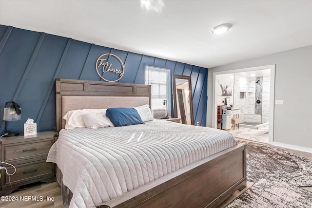 bedroom with ensuite bath and hardwood / wood-style floors