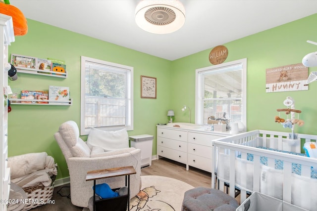 bedroom featuring light wood-type flooring and a crib