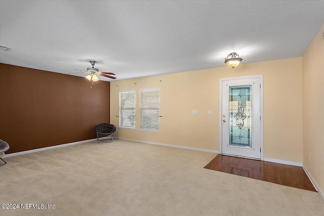 carpeted foyer featuring ceiling fan, a healthy amount of sunlight, and a textured ceiling