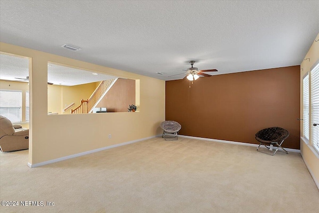 spare room featuring light carpet, a textured ceiling, and ceiling fan