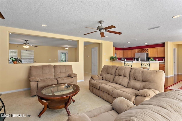 carpeted living room with a textured ceiling and ceiling fan