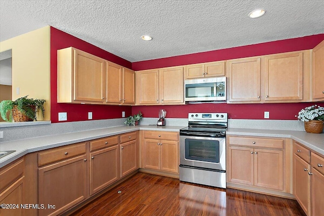 kitchen featuring appliances with stainless steel finishes, light brown cabinets, a textured ceiling, and dark hardwood / wood-style flooring