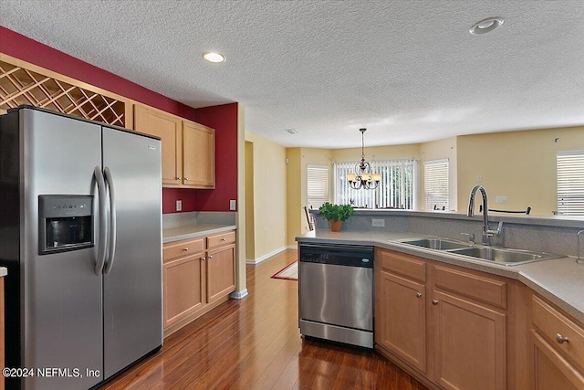 kitchen with sink, decorative light fixtures, a chandelier, appliances with stainless steel finishes, and dark hardwood / wood-style flooring