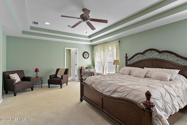 bedroom featuring light colored carpet, a tray ceiling, and ceiling fan