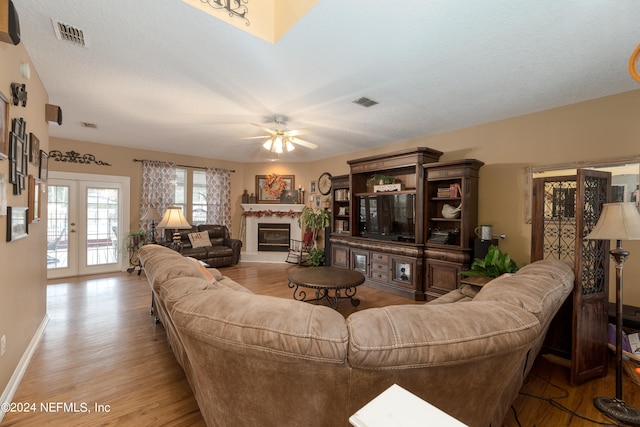 living room with french doors, a textured ceiling, light hardwood / wood-style floors, and ceiling fan