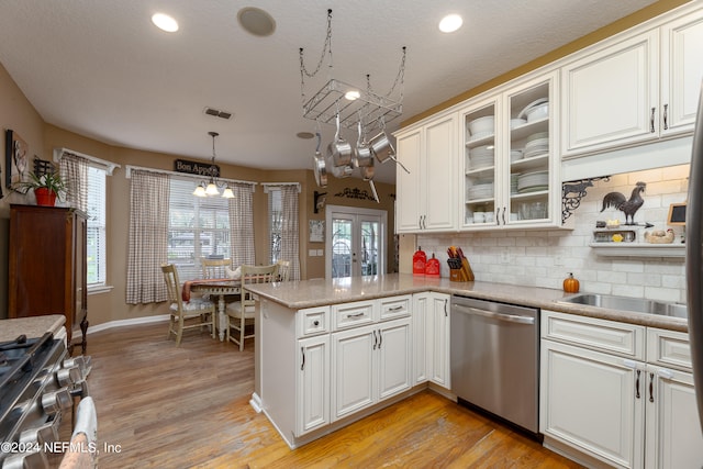 kitchen featuring white cabinets, hanging light fixtures, kitchen peninsula, light hardwood / wood-style flooring, and stainless steel appliances