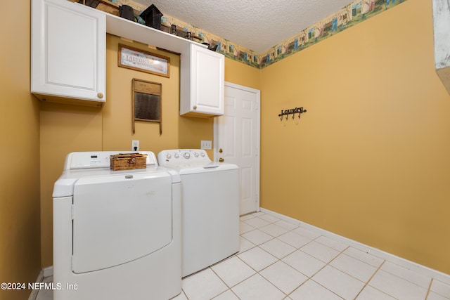 clothes washing area with independent washer and dryer, cabinets, light tile patterned floors, and a textured ceiling