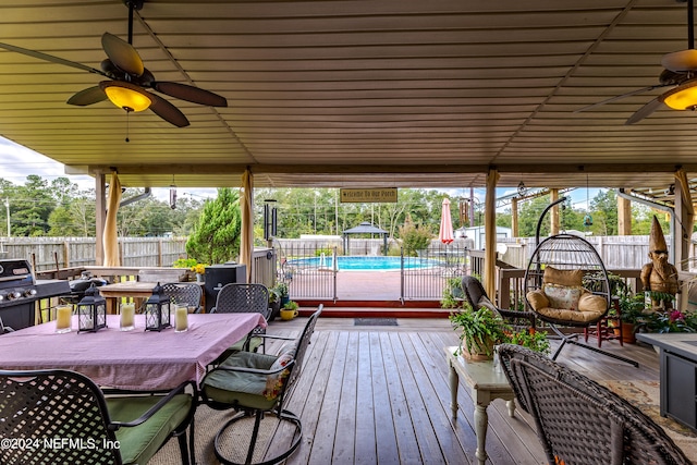 wooden terrace featuring a fenced in pool and ceiling fan