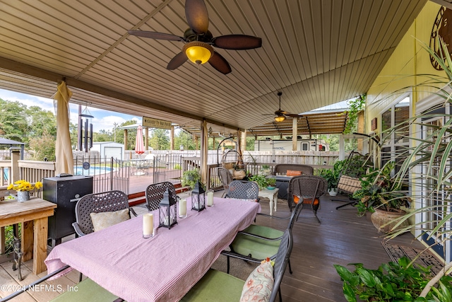 deck featuring ceiling fan and a pool