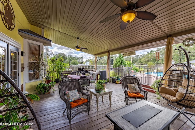 wooden deck with ceiling fan, a fenced in pool, and an outdoor living space