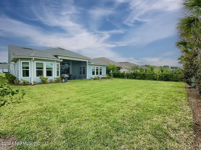 back of house with a yard and a sunroom