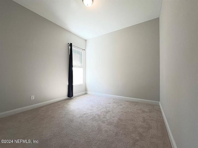 unfurnished room with baseboards and light colored carpet