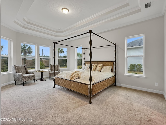 bedroom with a tray ceiling, light colored carpet, visible vents, and multiple windows