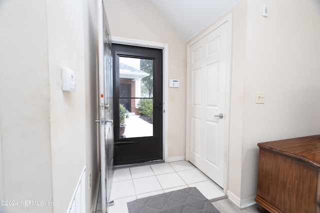 doorway featuring light tile patterned floors and vaulted ceiling