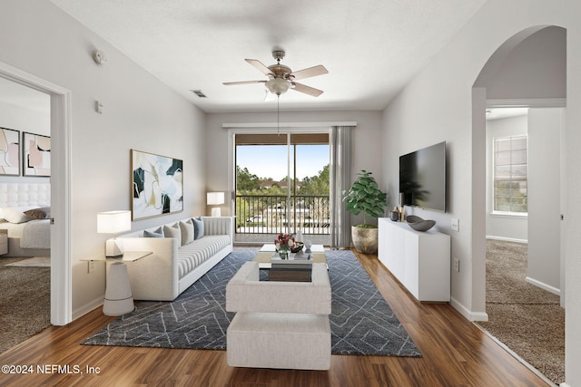 living room with dark hardwood / wood-style flooring and ceiling fan