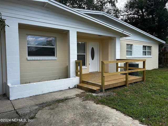 view of front facade with a deck, central air condition unit, and a front lawn