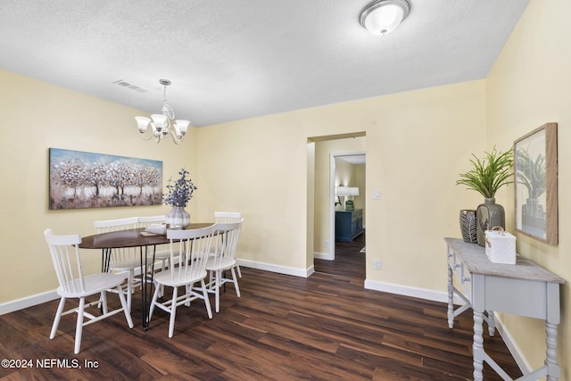 dining room featuring dark hardwood / wood-style flooring, a textured ceiling, and an inviting chandelier