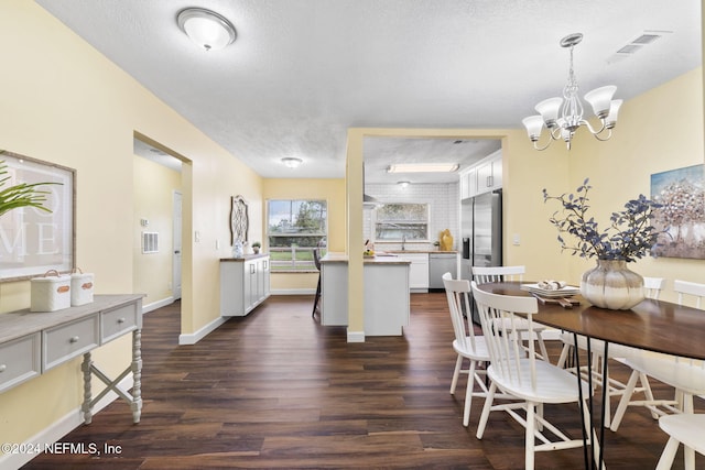 dining space with dark hardwood / wood-style floors, a textured ceiling, sink, and a notable chandelier