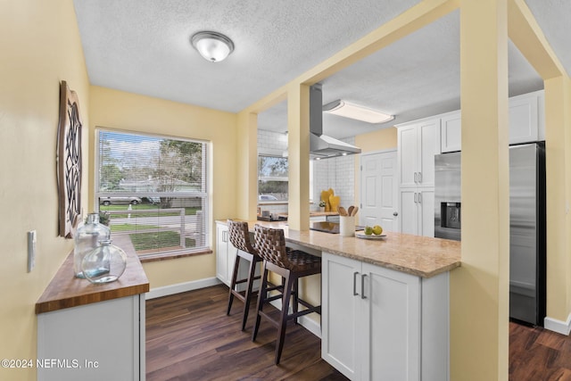 kitchen featuring white cabinetry, a textured ceiling, stainless steel fridge with ice dispenser, dark hardwood / wood-style floors, and a kitchen breakfast bar