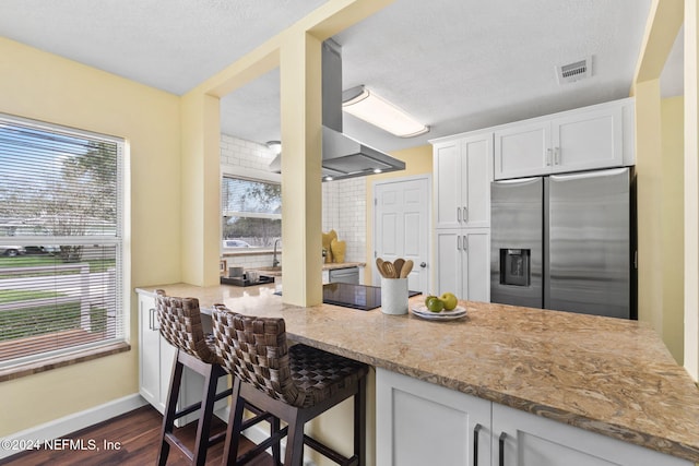 kitchen featuring stainless steel fridge, white cabinetry, and a healthy amount of sunlight