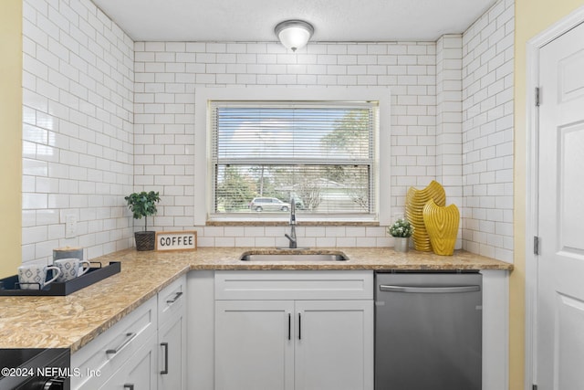 kitchen featuring stainless steel dishwasher, white cabinetry, sink, and tasteful backsplash