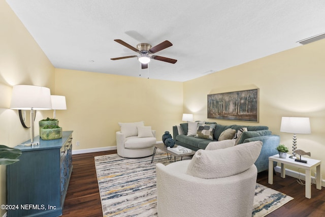 living room featuring dark wood-type flooring and ceiling fan