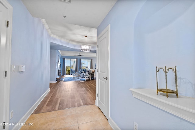 hall with crown molding, light hardwood / wood-style flooring, and a notable chandelier