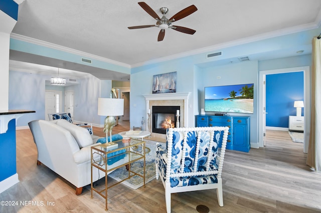 living room with light hardwood / wood-style floors, ornamental molding, and ceiling fan