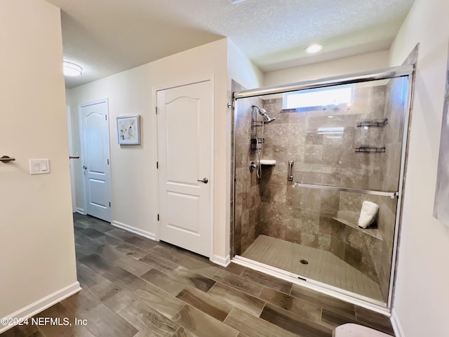 bathroom featuring a shower with door and a textured ceiling