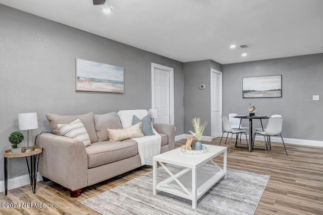 living room with light wood-type flooring and ceiling fan