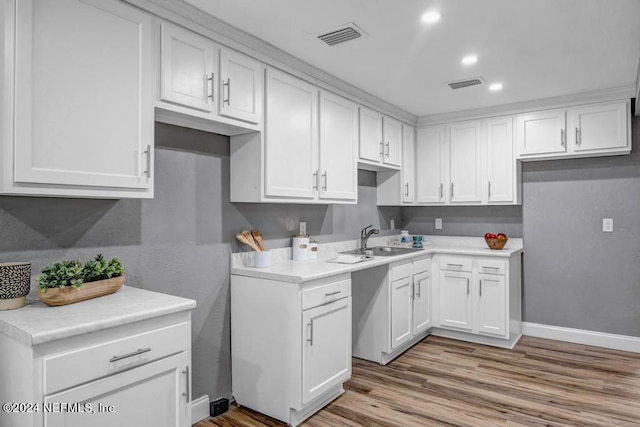 kitchen with light hardwood / wood-style floors, white cabinetry, and sink