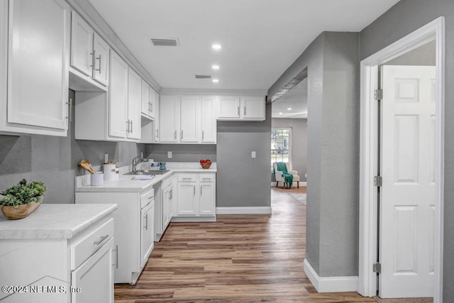 kitchen with dishwasher, sink, light hardwood / wood-style floors, and white cabinetry