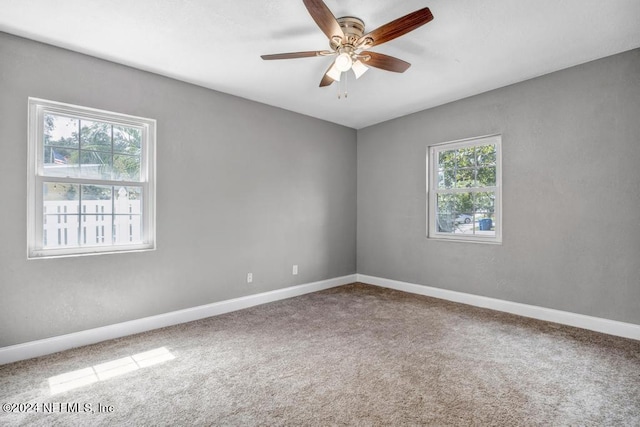 carpeted spare room featuring ceiling fan and plenty of natural light