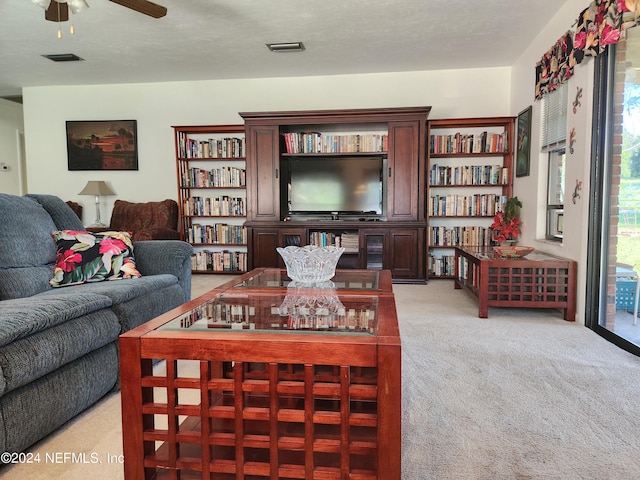 carpeted living room featuring ceiling fan and a textured ceiling