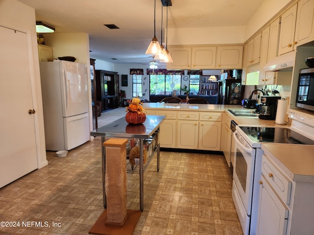 kitchen with decorative light fixtures, sink, white appliances, and kitchen peninsula