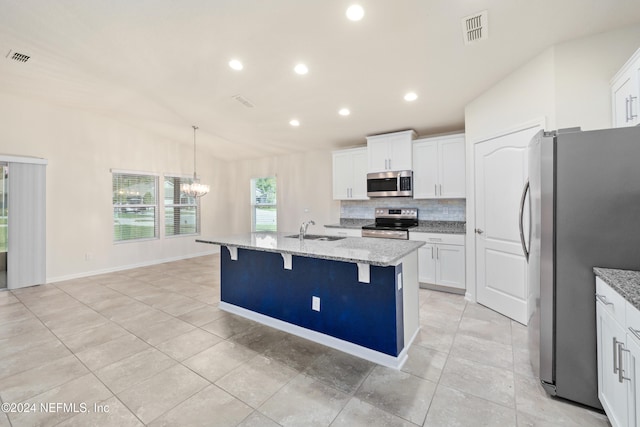 kitchen with a center island with sink, white cabinetry, stainless steel appliances, sink, and light stone counters