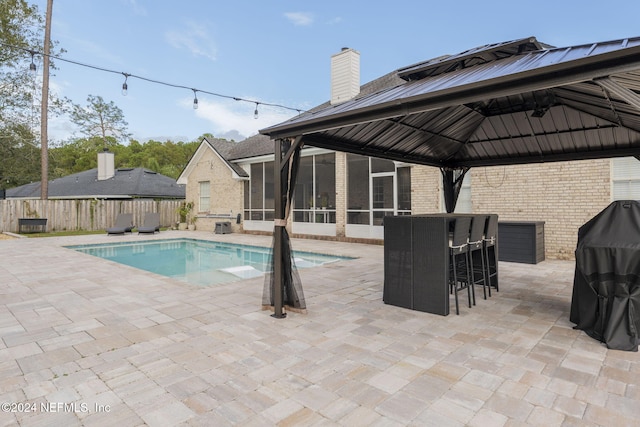 view of swimming pool with a sunroom, a patio, and a gazebo