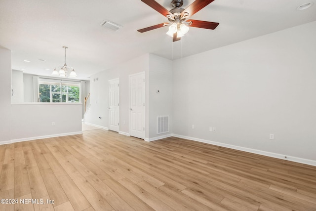 unfurnished room with light wood-type flooring and ceiling fan with notable chandelier