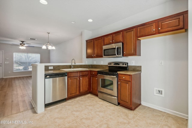 kitchen with light wood-type flooring, sink, ceiling fan with notable chandelier, hanging light fixtures, and appliances with stainless steel finishes